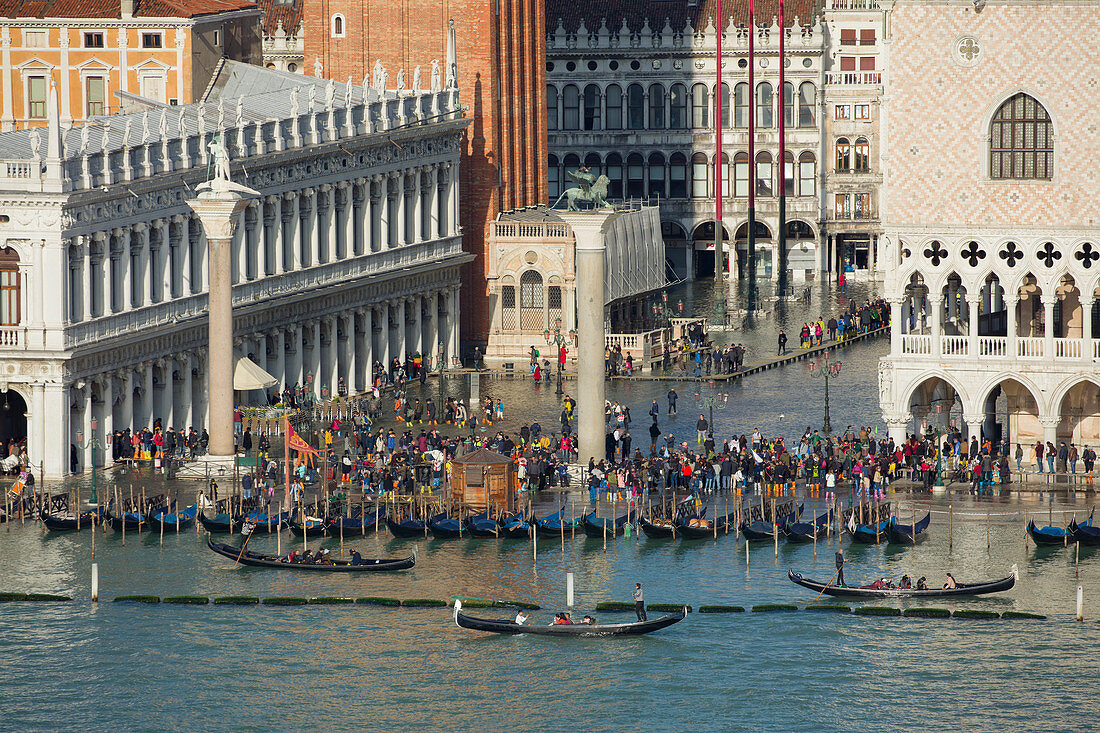 Erhöhte Ansicht eines belebten Markusplatzes in Venedig während der Flut mit Gondeln, die entlang der Küste, Venedig, UNESCO-Weltkulturerbe, Venetien, Italien, Europa aufgereiht werden