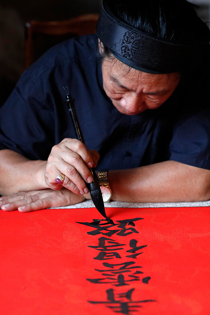 Mann, der traditionelle chinesische Schrift (Kalligraphie) in Tinte unter Verwendung eines Pinsels, der Tempel der Literatur, Hanoi, Vietnam, Indochina, Südostasien, Asien tut