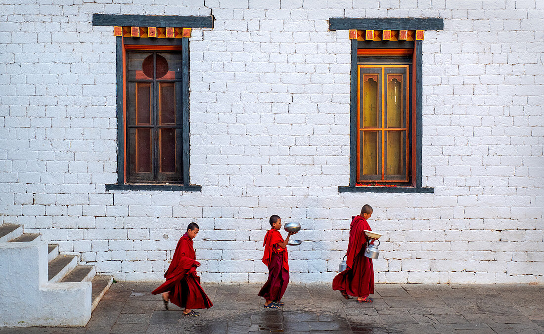 Three Buddhist monks carrying food bowls, Kyichu Temple, Bhutan, Asia
