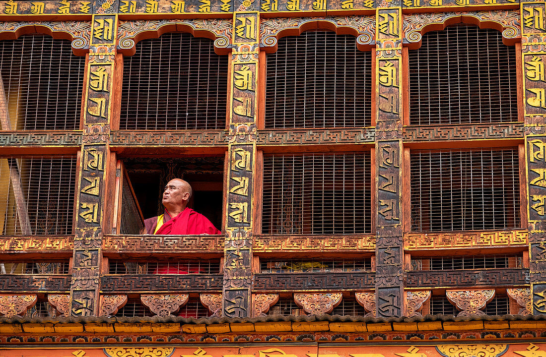 Portrait, mature Buddhist monk looking out of window, Punakha Dzong, Bhutan, Asia
