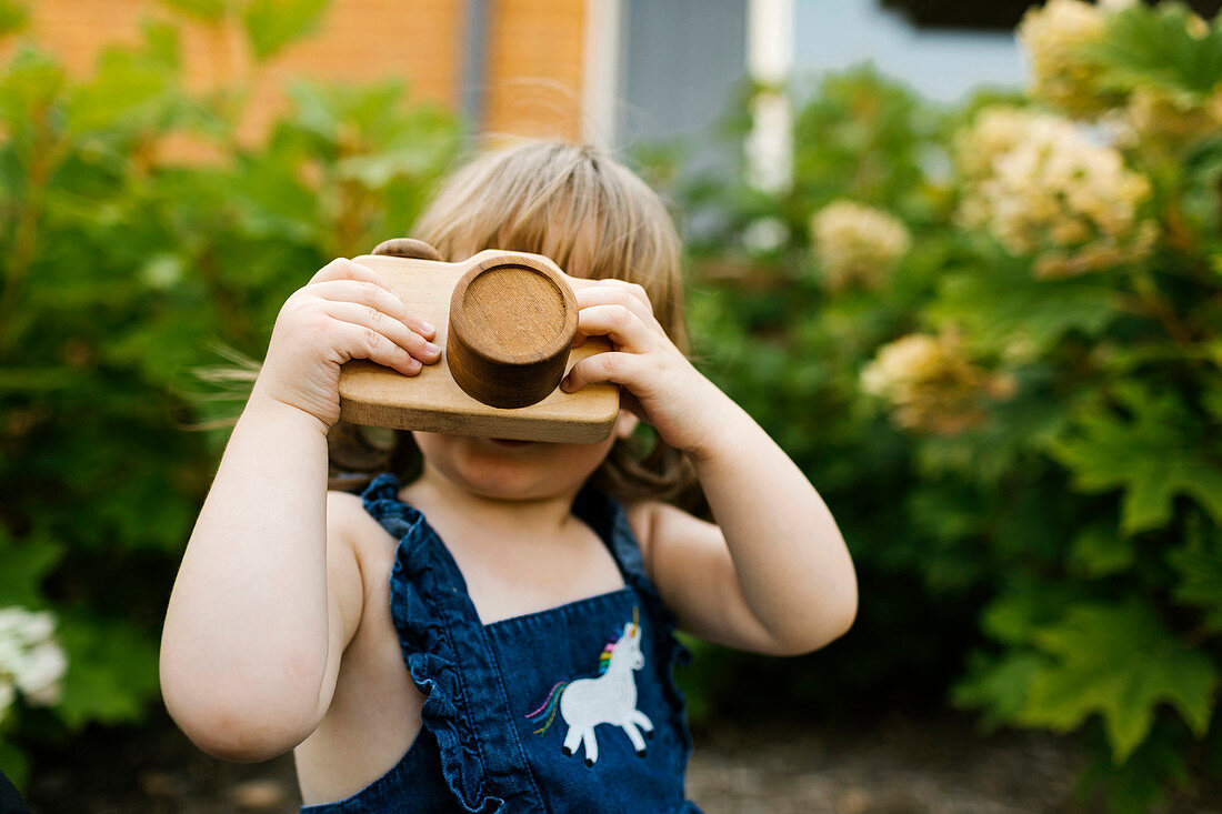 Kleines Mädchen mit Spielzeugkamera im Garten