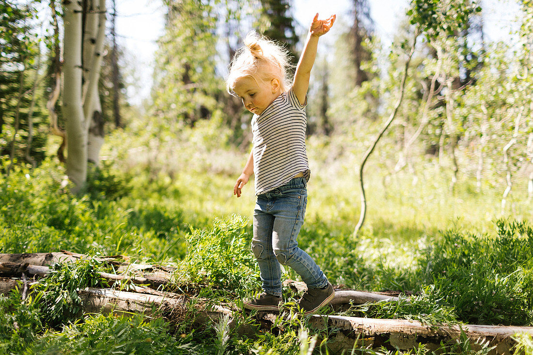 Mädchen balanciert auf Baumstamm im Wald, Uinta-Nationalpark, Utah, USA