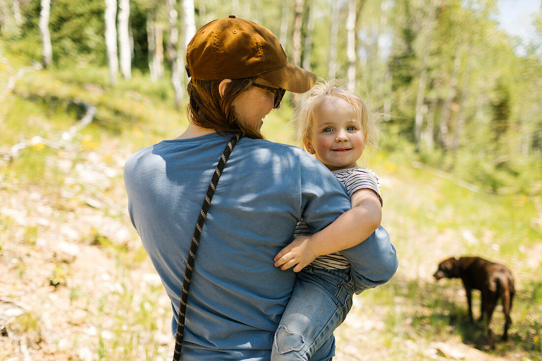 Frau hält kleine Tochter auf dem Arm in der Natur