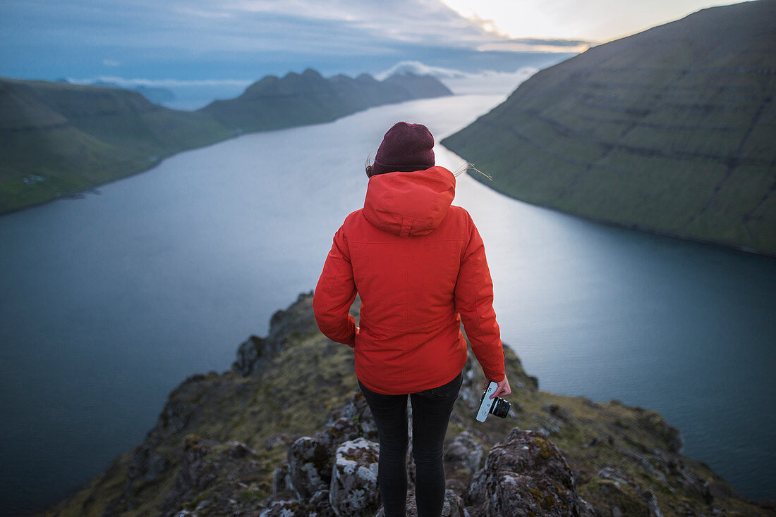 Frau steht auf Klakkur Berg und betrachtet den Fjord, Gjgv, Färöer, Dänemark