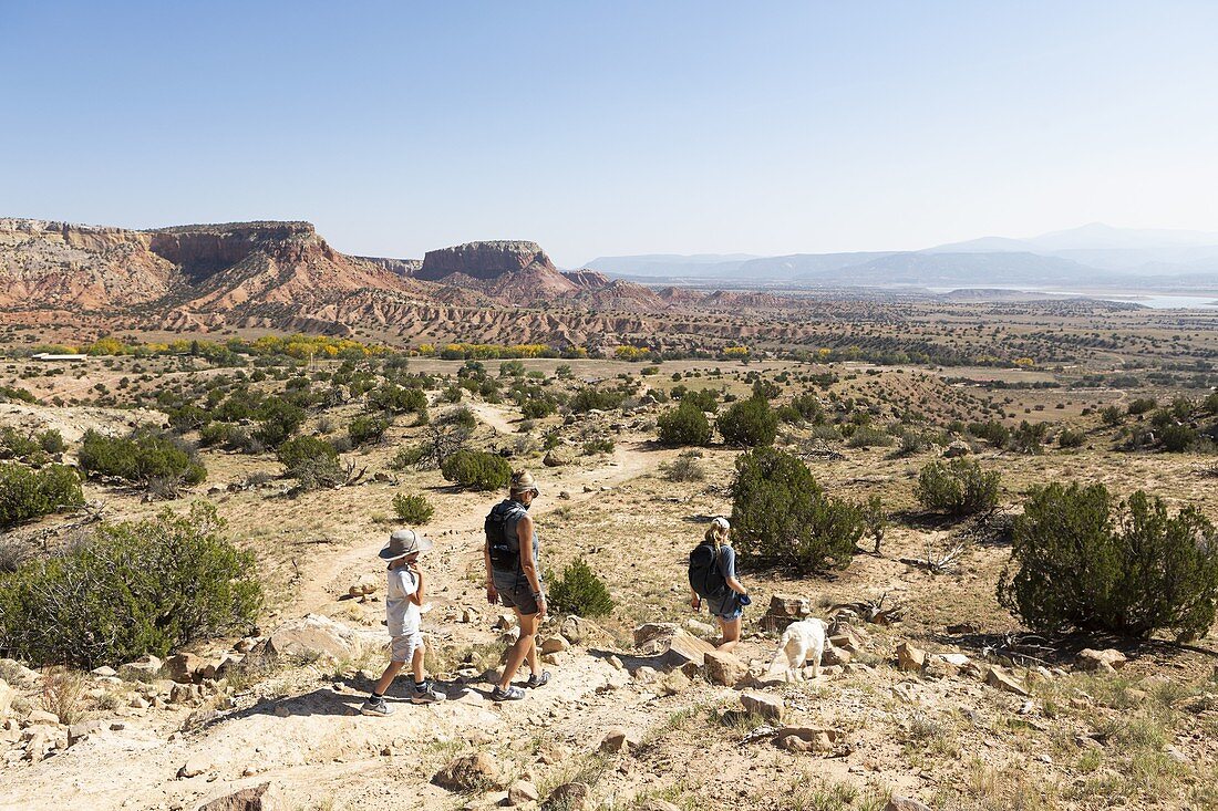 Familie mit drei Personen, die auf einem Pfad durch eine geschützte Canyonlandschaft wandert