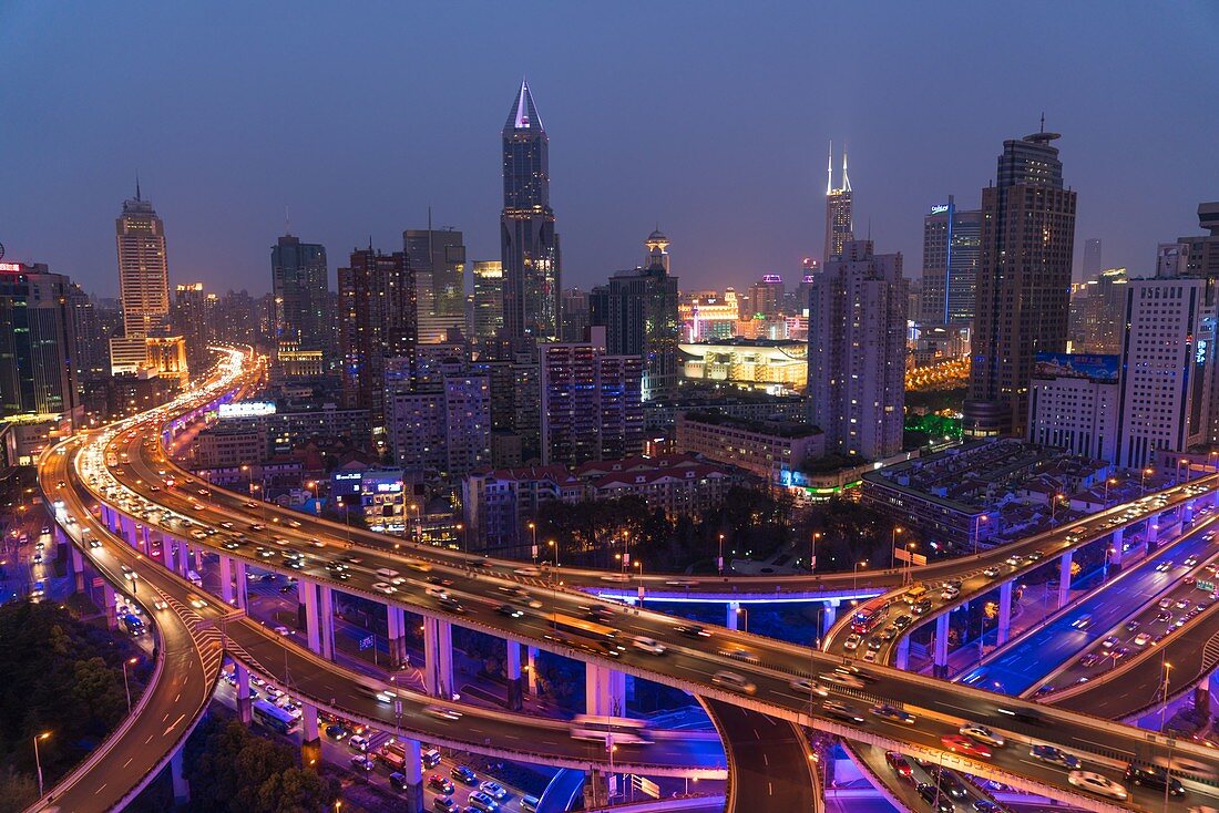 Elevated road junction and skyline of Shanghai, China at dusk.