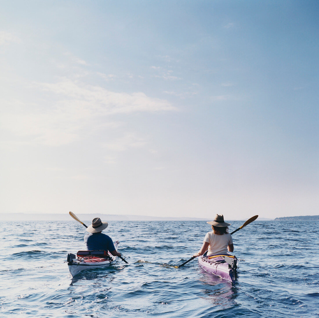 Mann und Frau mittleren Alters fahren Kajak auf ruhigem Gewässer