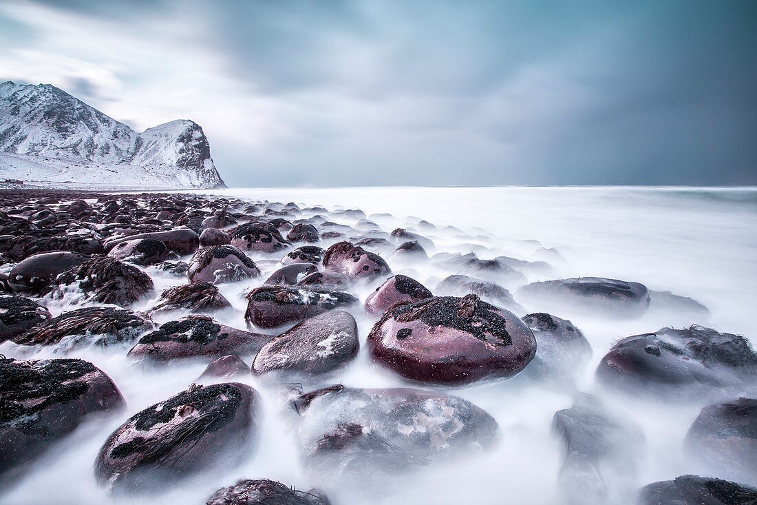 Vom Wind modellierte Felsen am Strand umgeben das eisige Meer Unstad Lofoten, Norwegen, Europa