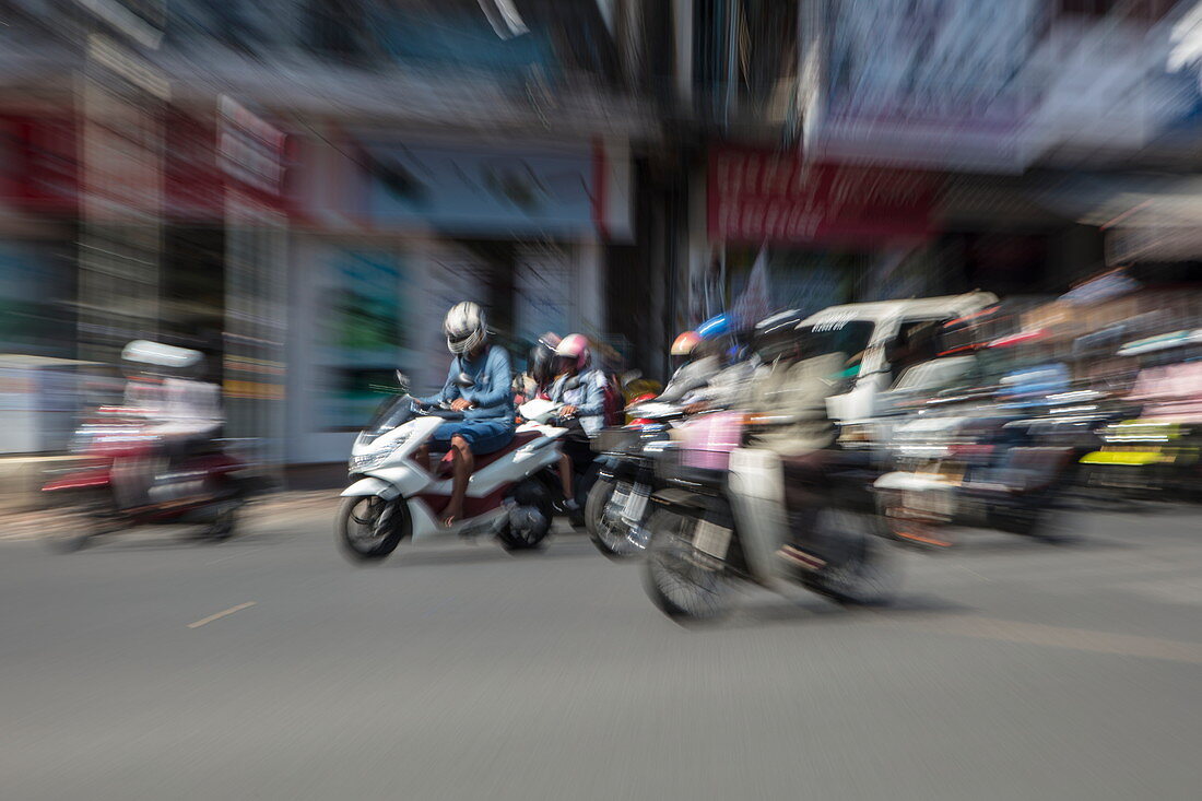 Zoomed image of people on mopeds on busy street, Phnom Penh, Cambodia, Asia