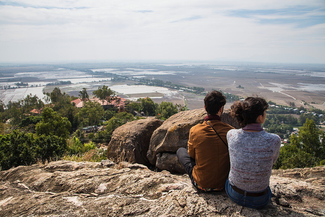 Couple looks out over rice fields near Vietnam and Cambodia border from Long Son Pagoda on Sam Mountain, near Chau Doc, An Giang, Vietnam, Asia
