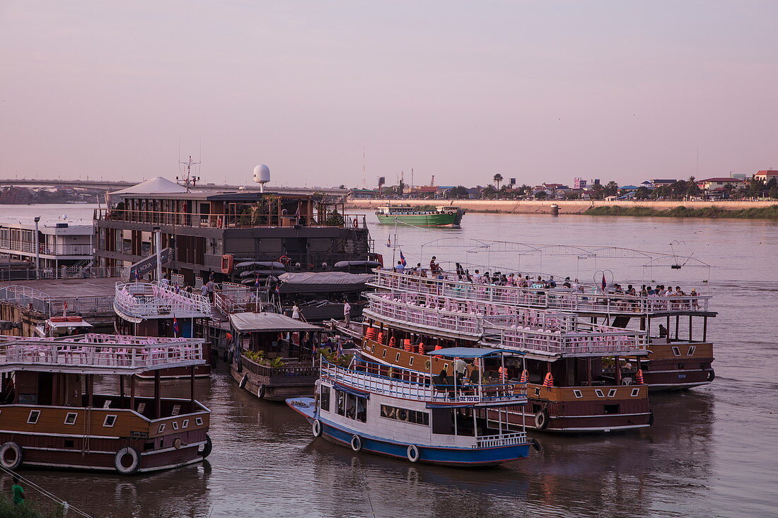 Flusskreuzfahrtschiff und Ausflugsboote festgemacht am schwimmenden Hafen von Phnom Penh bei Sonnenuntergang, Phnom Penh, Kambodscha, Asien