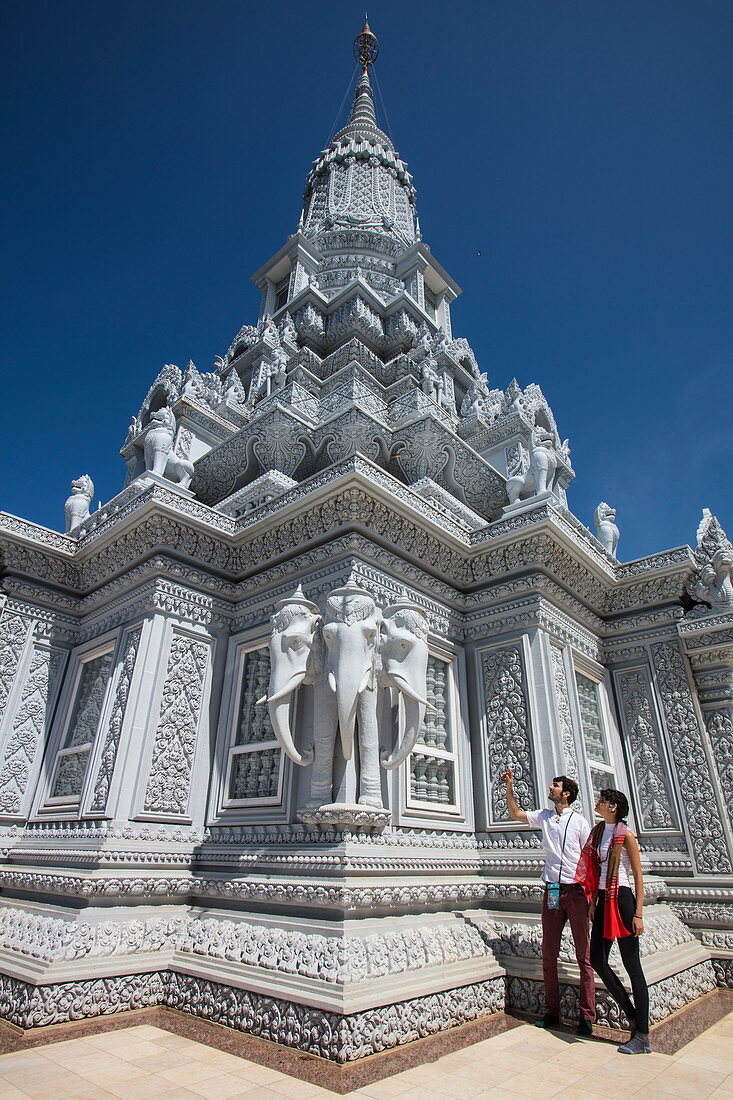 Young couple admires the ornate decoration with three-headed elephants on the stupa on Mount Phnom Oudong, Oudong (Udong), Kampong Speu, Cambodia, Asia