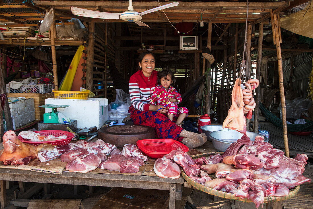 Cheerful woman with daughter at a butcher stall at the street market, Kampong Chhnang, Kampong Chhnang, Cambodia, Asia