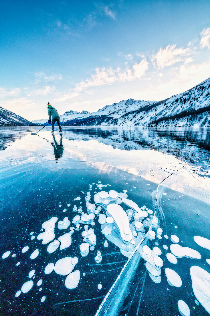 Mann, der Eishockey auf gefrorenem See Sils bedeckt von Blasen, Engadin, Kanton Graubunden, Schweiz, Europa spielt