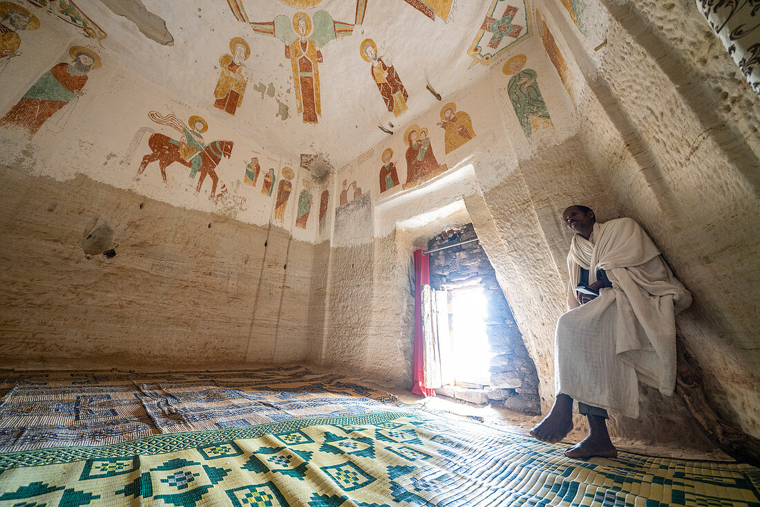 Orthodoxer Priester meditiert innerhalb der Felsenkirche von Daniel Korkor, Gheralta Mountains, Tigray Region, Äthiopien, Afrika
