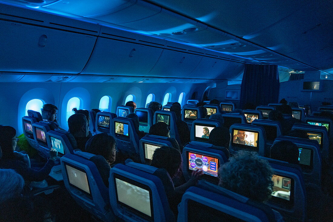 Passengers enjoy in-flight entertainment in Moana Economy Class on the Air Tahiti Nui Boeing 787 Dreamliner aircraft flying from Charles de Gaulle Airport in France to Los Angeles International Airport in the United States