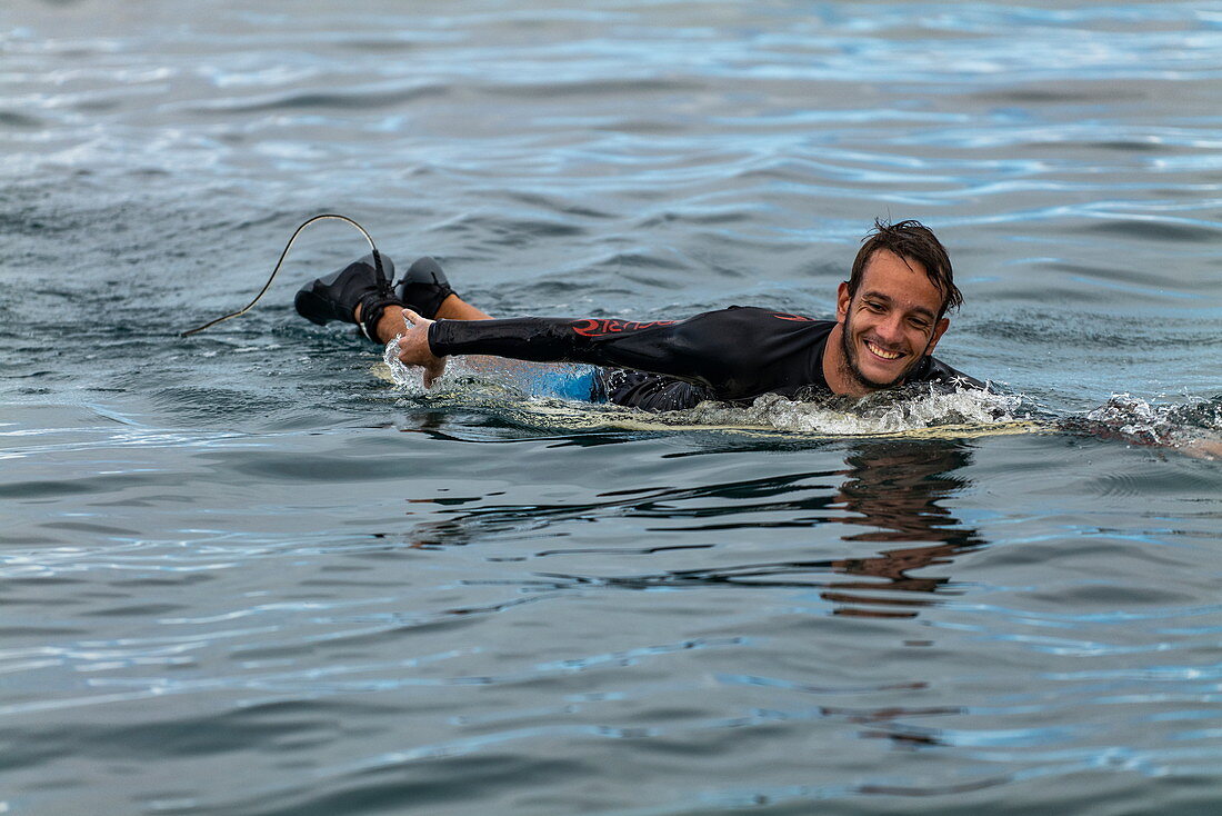 Ein Surfer paddelt im Wasser am Surfgebiet Teahupoo, Tahiti Iti, Tahiti, Windward Islands, Französisch-Polynesien, Südpazifik