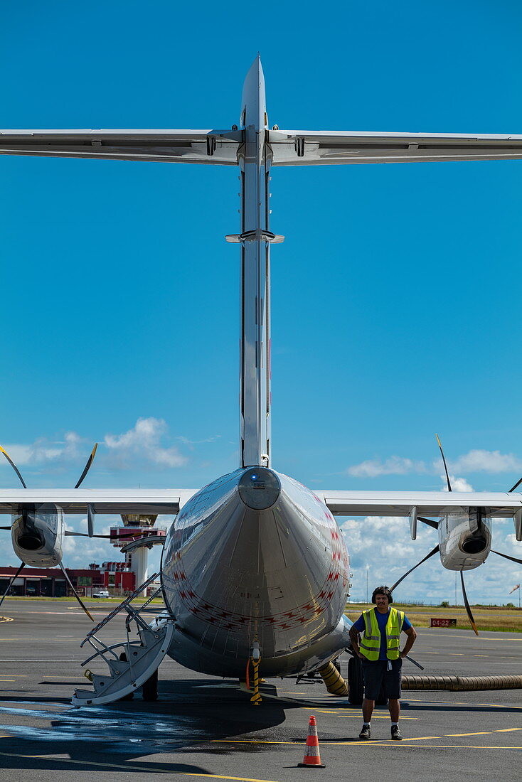Bodenarbeiter steht bei Air Tahiti ATR 72-600 Flugzeug am Vorfeld des internationalen Flughafens Tahiti Faa'a (PPT), Papeete, Tahiti, Windward Islands, Französisch-Polynesien, Südpazifik