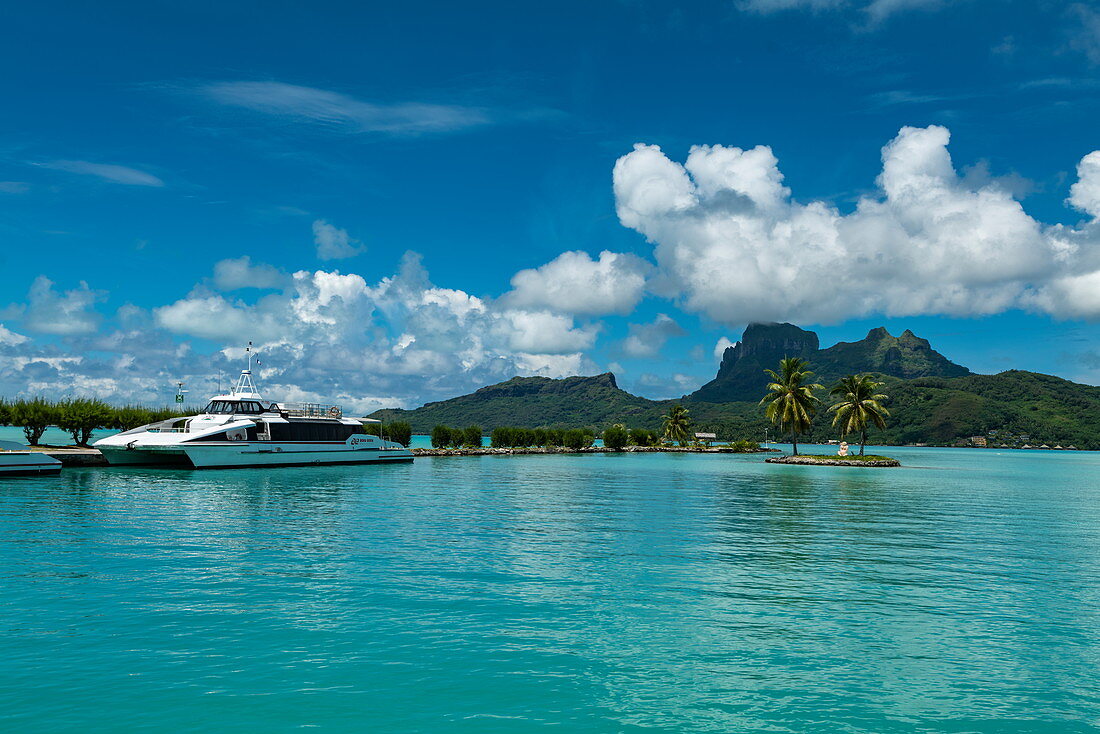 Katamaranfähre Bora Bora Navettes am Pier von Flughafen Bora Bora (BOB) mit türkisfarbenem Lagunenwasser und Mount Otemanu in der Ferne, Bora Bora, Leeward Islands, Französisch-Polynesien, Südpazifik
