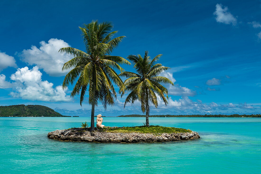 Zwei Palmen und eine Tiki Skulptur auf einer kleinen Insel am Eingang zum Hafen von Flughafen Bora Bora (BOB), Bora Bora, Leeward Islands, Französisch-Polynesien, Südpazifik