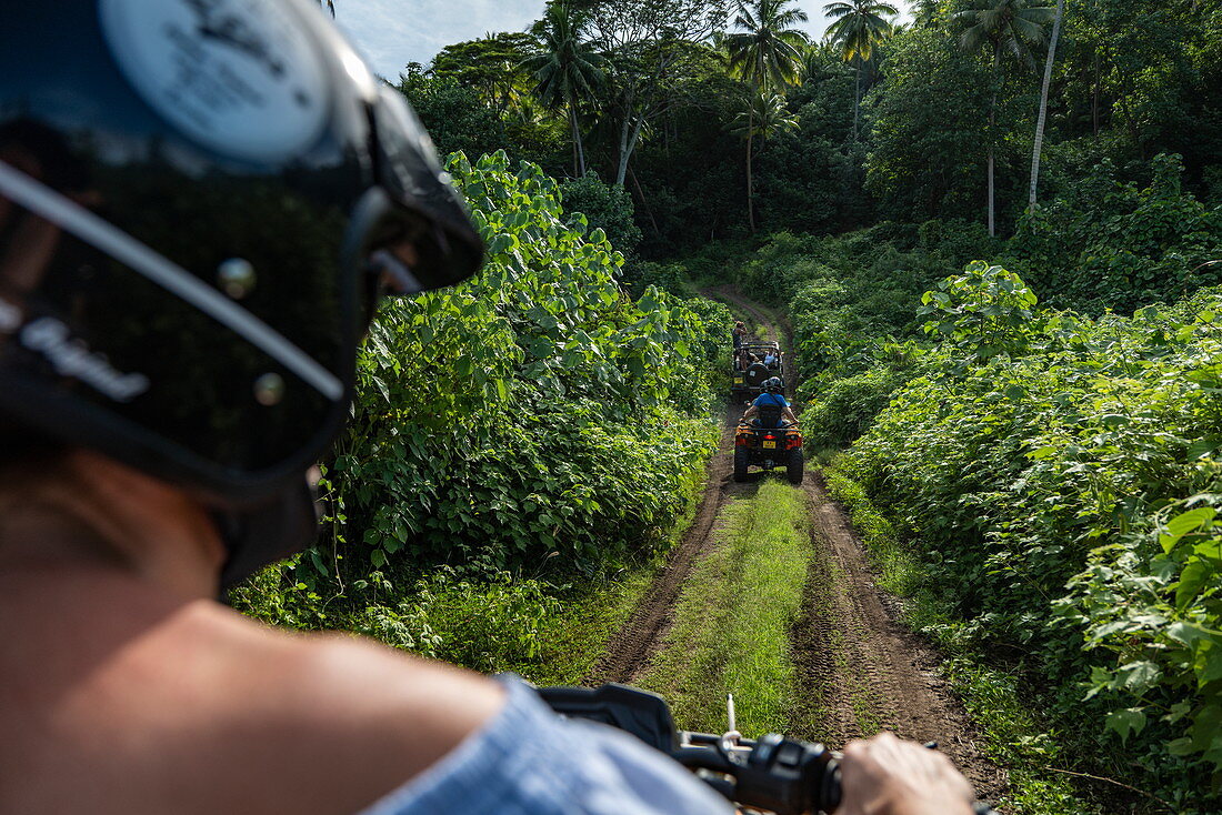 Looking over the shoulder during an excursion in a quad all-terrain vehicle on a dirt road through lush mountain vegetation, Bora Bora, Leeward Islands, French Polynesia, South Pacific