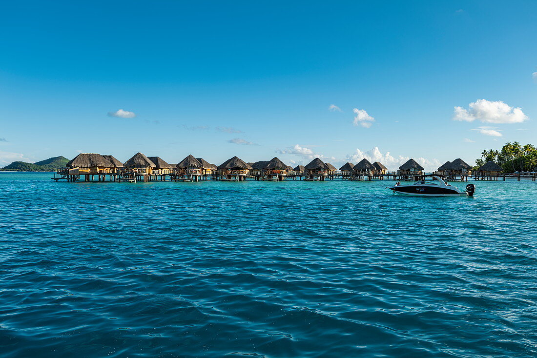 Small motorboat in the Bora Bora lagoon with overwater bungalows at the Bora Bora Pearl Beach Resort, Bora Bora, Leeward Islands, French Polynesia, South Pacific