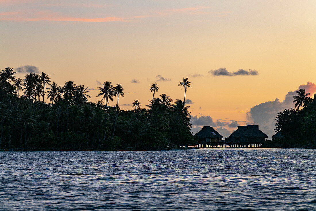 Silhouette von Überwasserbungalows entlang Lagune von Bora Bora bei Sonnenuntergang, Bora Bora, Leeward Islands, Französisch-Polynesien, Südpazifik