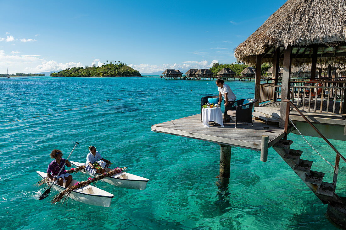 Frühstück wird mit einem Pirogue Auslegerkanu zu einem Überwasserbungalow des Sofitel Bora Bora Private Island Resorts in der Lagune von Bora Bora gebracht, Bora Bora, Leeward Islands, Französisch-Polynesien, Südpazifik serviert
