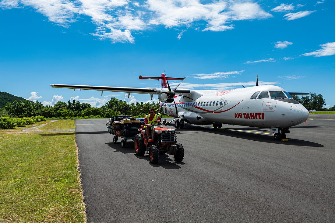 Tractor with luggage in front of Air Tahiti ATR 72-600 aircraft on apron at Moorea Airport (MOZ), Windward Islands, French Polynesia, South Pacific