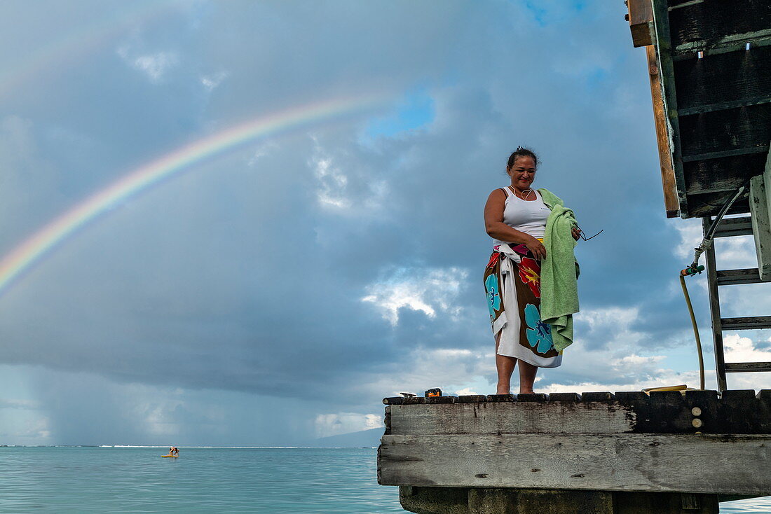 Tahitianerin am Pier mit Regenbogen dahinter, Moorea, Windward Islands, Französisch-Polynesien, Südpazifik