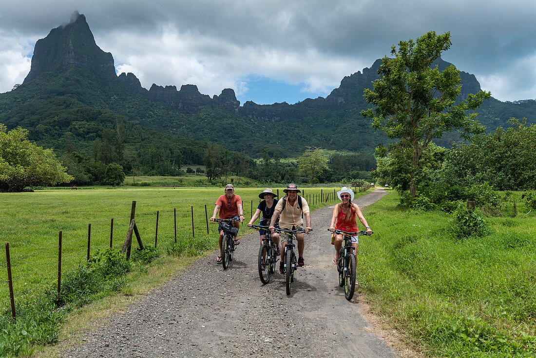 Two couples enjoy a bike ride into the interior of the island with Mount Tohivea behind, Moorea, Windward Islands, French Polynesia, South Pacific