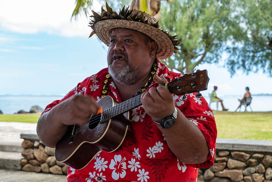 Mann spielt Ukulele Gitarre und heißt Kreuzfahrtpassagiere willkommen, Moorea, Windward Islands, Französisch-Polynesien, Südpazifik