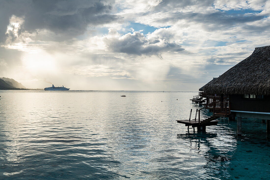 Cruise ship leaves Opunohu Bay during a thunderstorm with overwater bungalows at the Hilton Moorea Lagoon Resort & Spa, Moorea, Windward Islands, French Polynesia, South Pacific