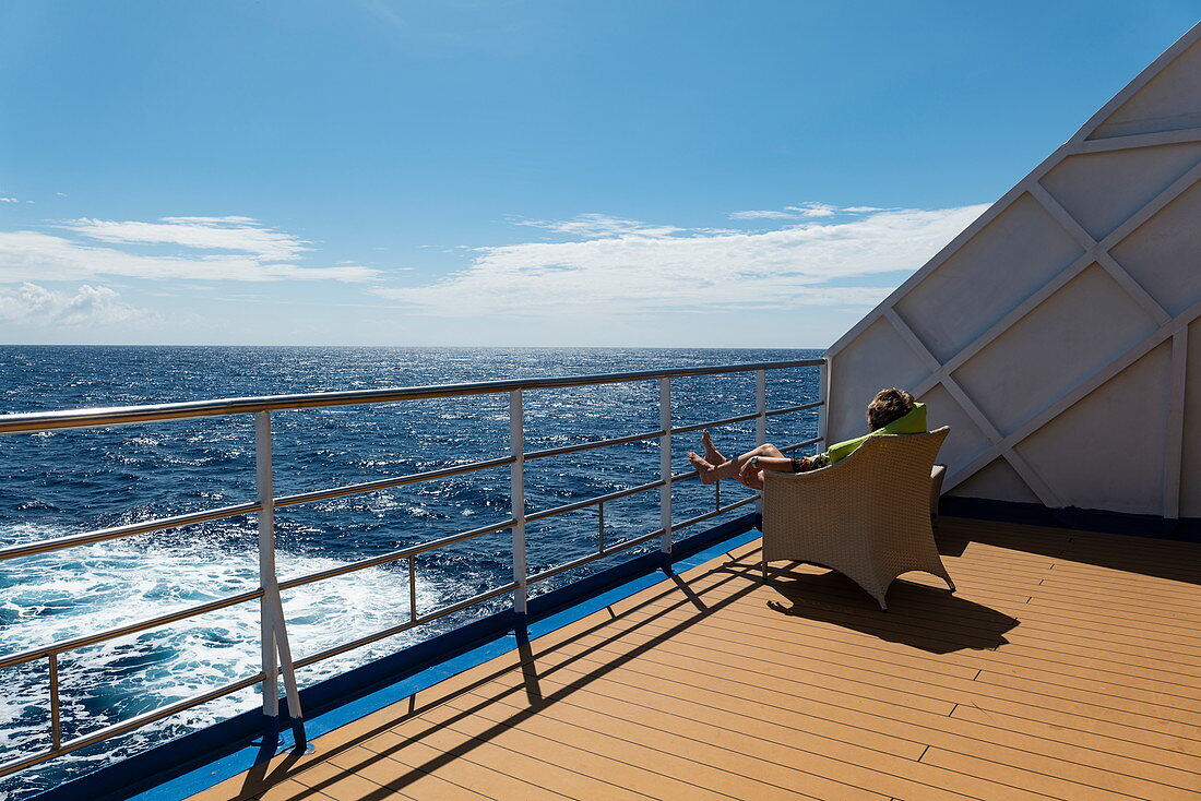 Frau entspannt sich an Deck von Passagierfrachtschiff Aranui 5 (Aranui Cruises), auf See zwischen den Marquesas-Inseln und den Tuamotu-Inseln, Französisch-Polynesien, Südpazifik