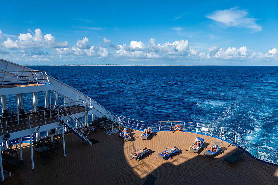 Menschen entspannen sich auf dem hinteren Sonnendeck von Passagierfrachtschiff Aranui 5 (Aranui Cruises), auf See zwischen den Tuamotu-Inseln und den Leeward Islands, Französisch-Polynesien, Südpazifik