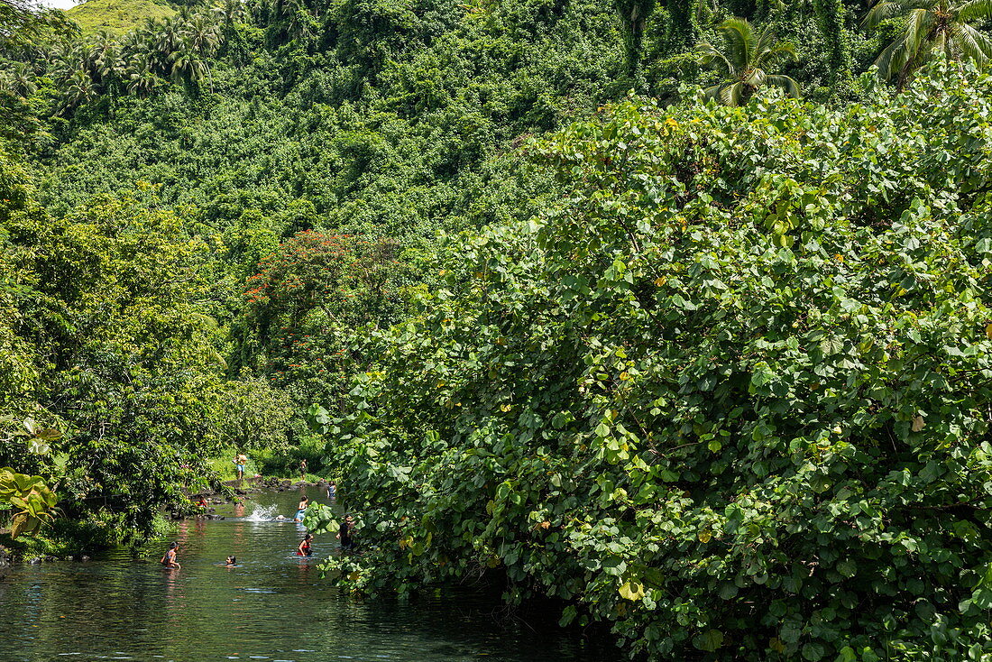 Kinder spielen im Fluss inmitten üppiger Vegetation, nahe Taravao, Tahiti, Windward Islands, Französisch-Polynesien, Südpazifik