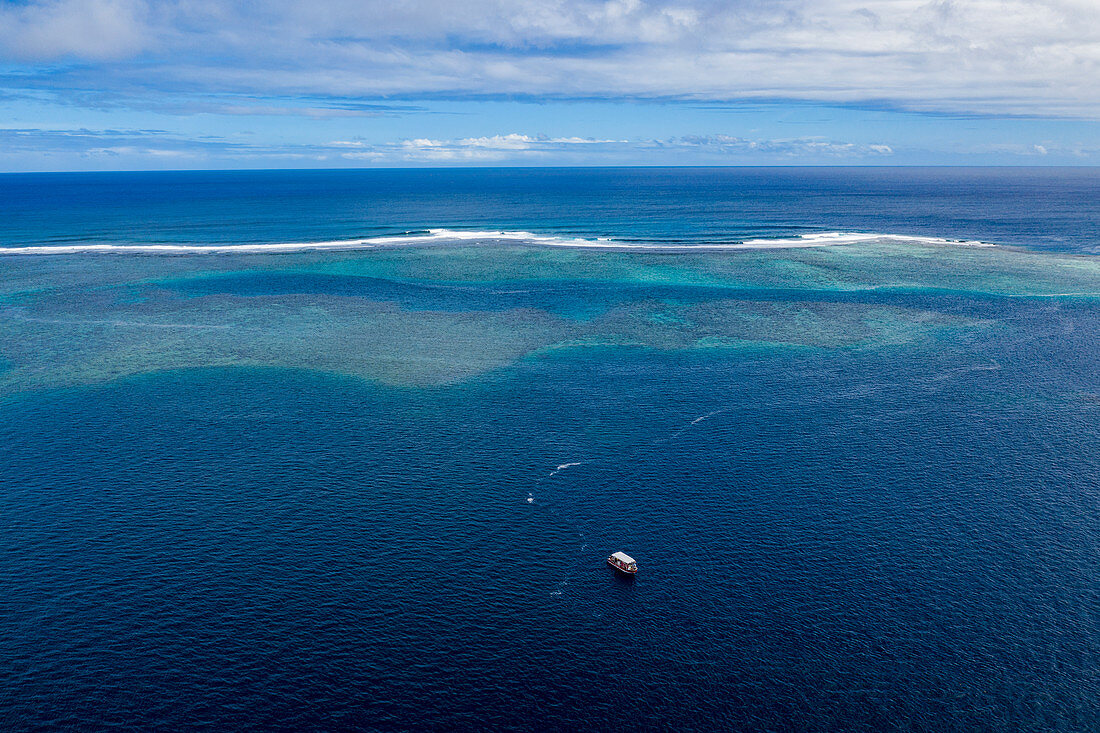 Luftaufnahme eines Ausflugsboots an der Südwestküste von Tahiti-Iti mit Riff in der Ferne, Pointe Puforatiai, Tahiti, Windward Islands, Französisch-Polynesien, Südpazifik