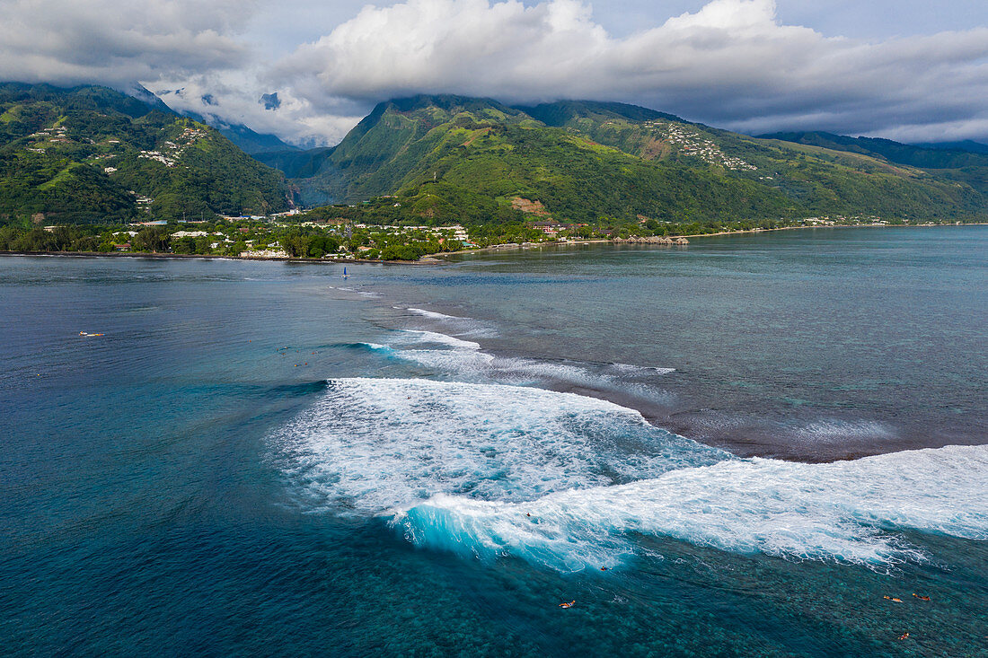 Luftaufnahme von Surfern auf Welle am Riff mit Küste und Bergen dahinter, Nuuroa, Tahiti, Windward Islands, Französisch-Polynesien, Südpazifik
