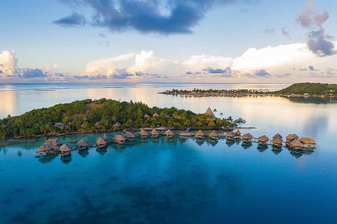 Luftaufnahme des Sofitel Bora Bora Private Island Resort mit Überwasserbungalows in der Lagune von Bora Bora bei Sonnenaufgang, Vaitape, Bora Bora, Leeward Islands, Französisch-Polynesien, Südpazifik