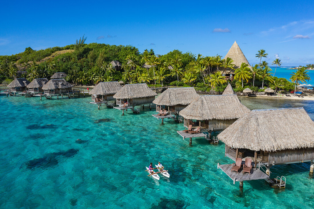 Aerial view of how breakfast is brought by pirogue outrigger canoe to an overwater bungalow of the Sofitel Bora Bora Private Island Resort in the Bora Bora Lagoon, Bora Bora, Leeward Islands, French Polynesia, South Pacific
