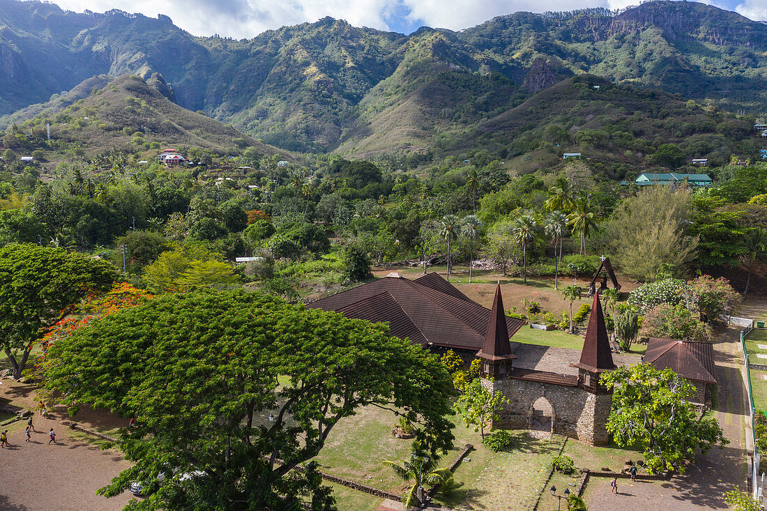 Aerial view of Notre Dame Cathedral with mountains behind, Taiohae, Nuku Hiva, Marquesas Islands, French Polynesia, South Pacific