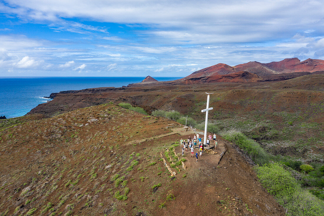 Luftaufnahme von weißem Kreuz auf Hügel mit Passagieren vom Passagierfrachter Aranui 5 (Aranui Cruises), Tekoapa, Ua Huka, Marquesas-Inseln, Französisch-Polynesien, Südpazifik