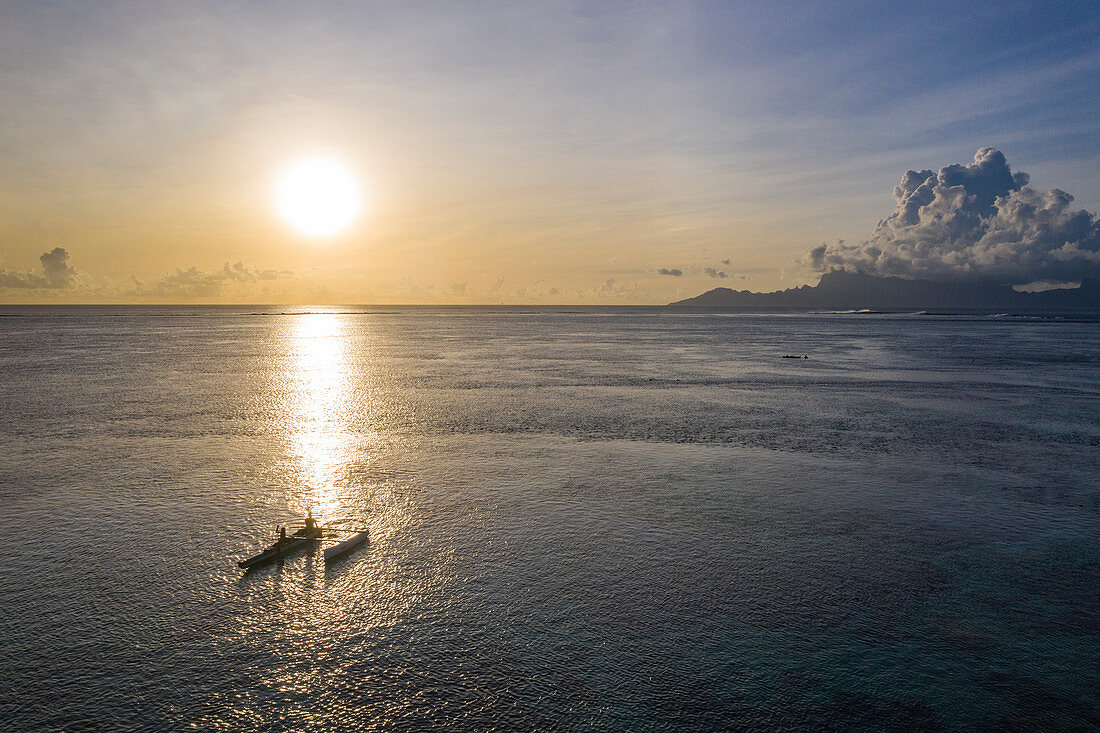 Luftaufnahme eines Auslegerkanus in der Lagune bei Sonnenuntergang mit Insel Moorea in der Ferne, nahe Papeete, Tahiti, Windward Islands, Französisch-Polynesien, Südpazifik