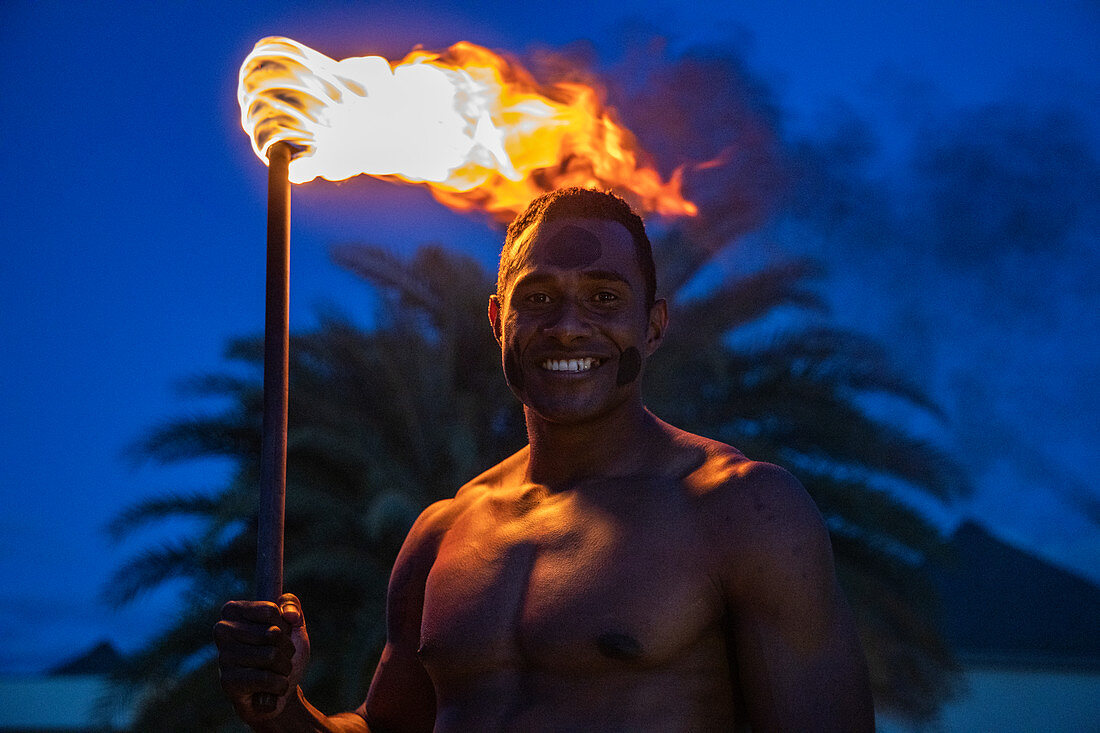 Friendly Fijian &quot;warrior&quot; with torch to light Tiki torches at Pullman Nadi Bay Resort