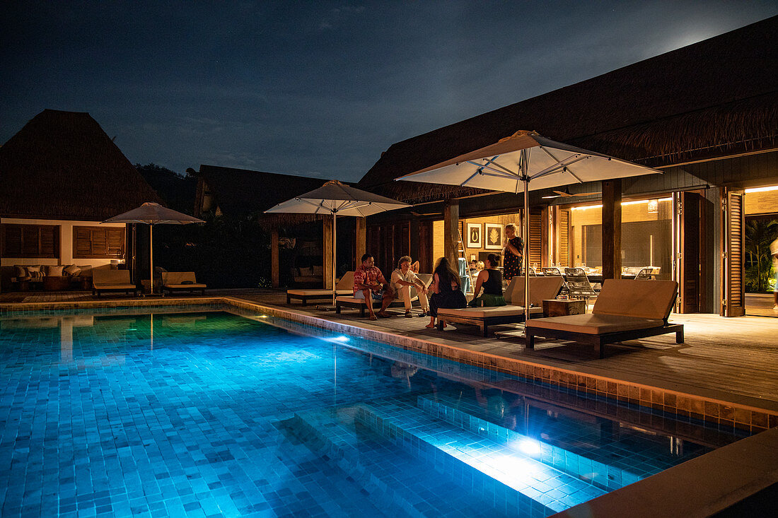 Menschen entspannen sich am privaten Swimming Pool einer Residence Villa Unterkunft im Six Senses Fiji Resort bei Nacht, Malolo Island, Mamanuca Group, Fidschi-Inseln, Südpazifik