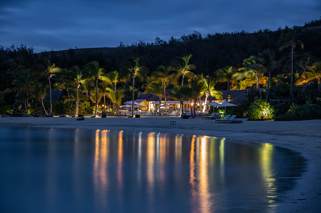 Strand und Spiegelung von Kokospalmen und Six Senses Fiji Resort in der Bucht in der Abenddämmerung, Malolo Island, Mamanuca Group, Fidschi-Inseln, Südpazifik