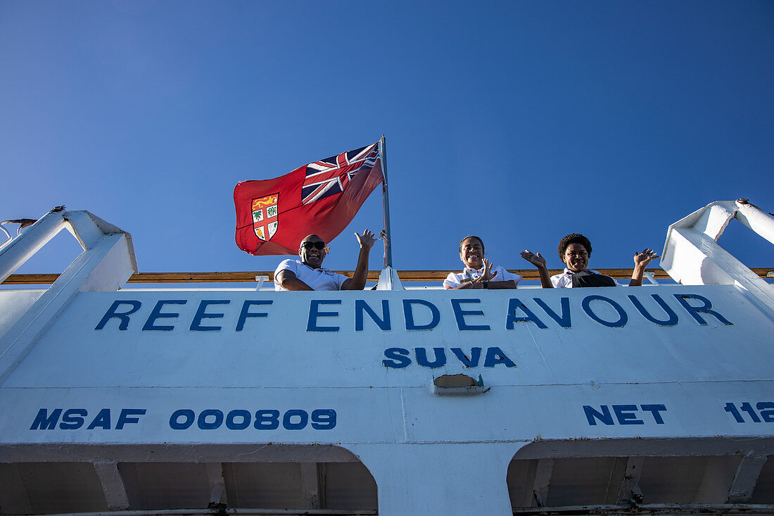 Crew waves goodbye from the deck of the cruise ship MV Reef Endeavor (Captain Cook Cruises Fiji), near Naviti Island, Yasawa Group, Fiji Islands, South Pacific