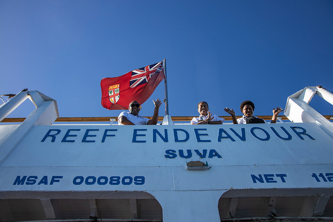 Crew winkt zum Abschied von Deck des Kreuzfahrtschiff MV Reef Endeavour (Captain Cook Cruises Fiji), nahe Naviti Island, Yasawa Group, Fidschi-Inseln, Südpazifik