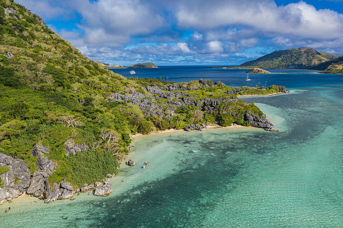 Luftaufnahme von Seite des Sawa-i-Lau Mountain mit dem Kreuzfahrtschiff MV Reef Endeavour (Captain Cook Cruises Fiji) in der Ferne, Sawa-i-Lau Island, Yasawa Group, Fidschi-Inseln, Südpazifik