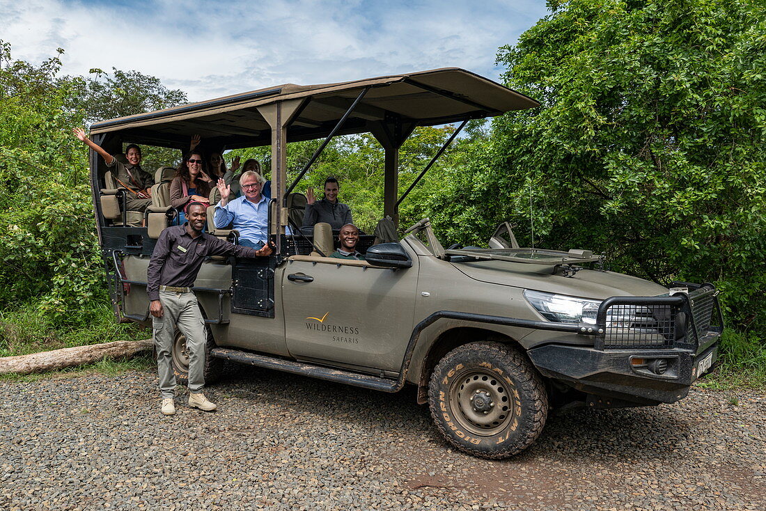 Group photo of happy visitors in safari vehicle operated by luxury resort tented Magashi Camp (Wilderness Safaris), Akagera National Park, Eastern Province, Rwanda, Africa